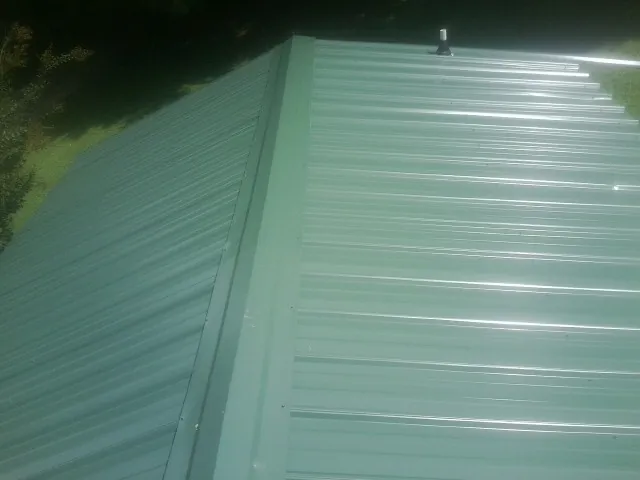 New green metal panels meeting at the ridge of a roof — Flat Roof Repair work by our crew in Intercession City