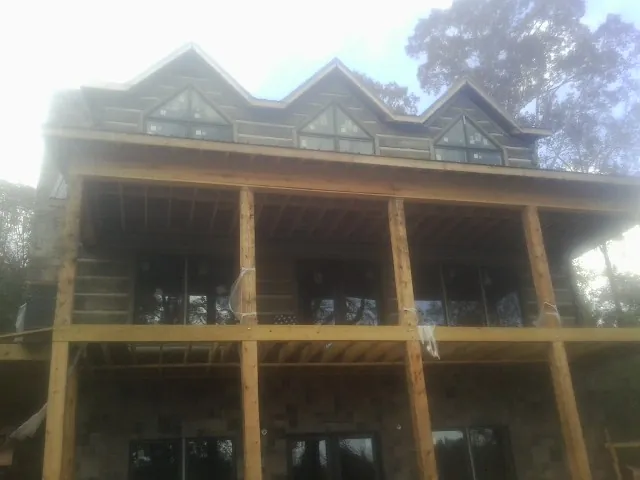 Dormers and porch framing on a large log home under construction — Roof Coating work by our crew in Intercession City