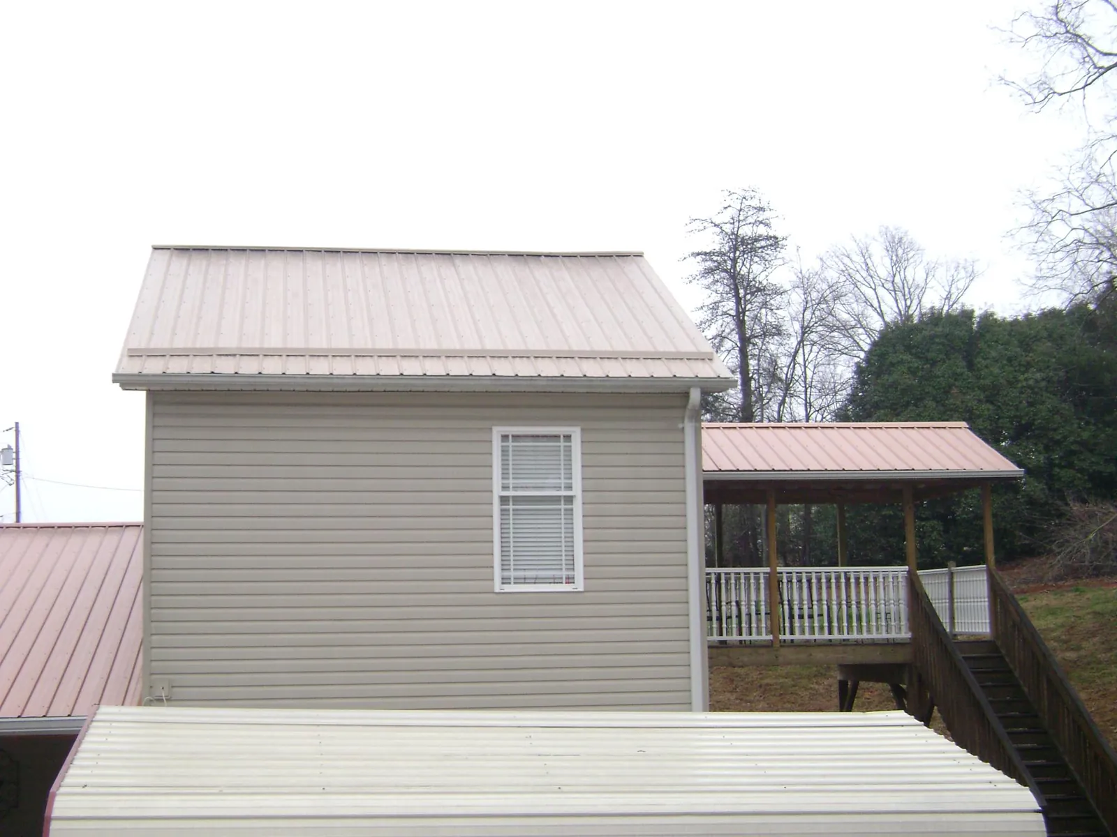 Tan metal roofs on a two story addition and attached porch, from a Roof Replacement job in Intercession City